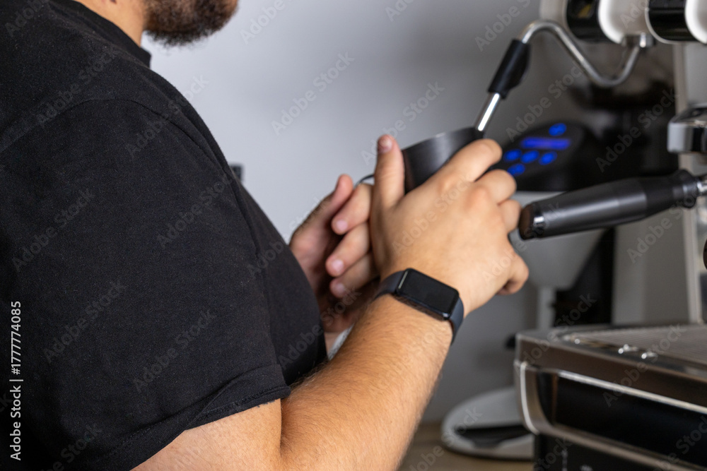 Obraz premium Close up of barista frothing milk with steam wand in modern cafe. Specialty beverage preparation concept with professional espresso equipment and warm lighting.