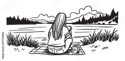 A woman with long hair sits on a blanket by a lake, holding a mug and enjoying the scenic view of mountains and trees.