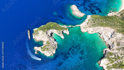 Aerial drone photo of not so famous paradise bay and caves of Saint Andrews islet creating a blue lagoon visited by yachts and small boats in the Northern part of Zakinthos island, Ionian Sea, Greece