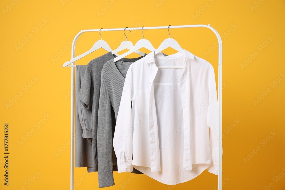 Obraz premium Different clothes hanging on rack against orange background
