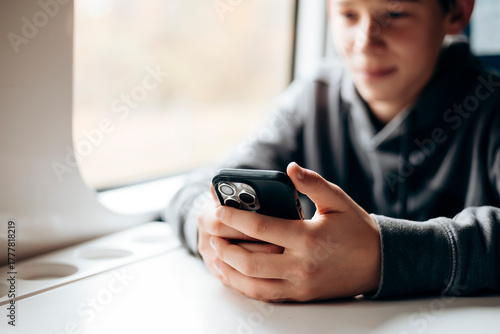 Young traveler holding smartphone on a train ride.