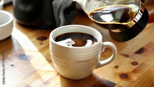 Pouring Fresh Coffee into a Mug on a Wooden Table in Morning Light