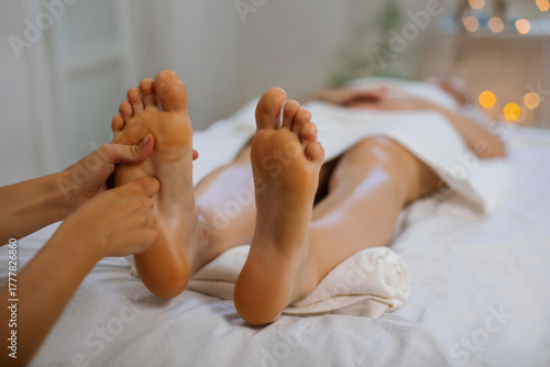 Skilled woman reflexologist massaging female feet in cozy spa center, pressing lady's feet soles, affecting energy flow points, closeup shot