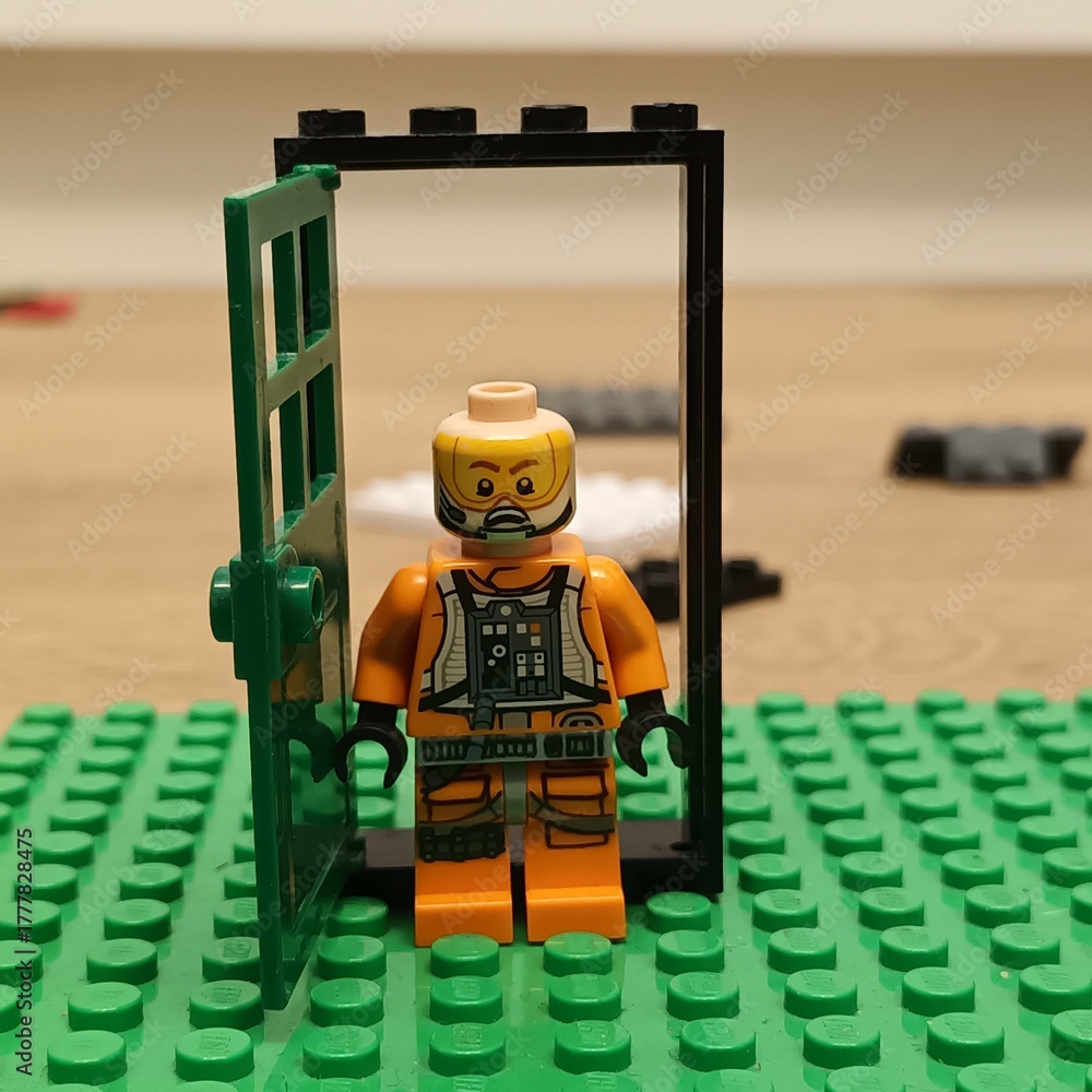 Naklejka premium LEGO® minifigure in a doorway constructed from LEGO® bricks, with green baseplate, indoors, daytime