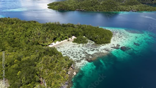 Aerial view of tropical beach resort with wooden bungalows surrounded by turquoise lagoons and green islands in Raja Ampat, Indonesia.	