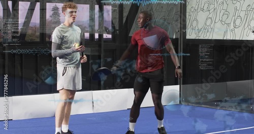 Padel coach tossing ball to trainee, guiding volley drills on blue court for training and laughter
