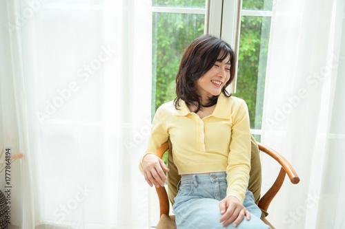 Free Download Smiling Woman Relaxing on a Couch in a Bright, Cozy Living Room - GFXLoad