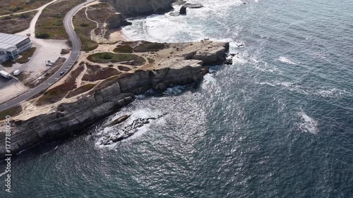 coastline with rocks jutting into the ocean, foaming waves along the shore.