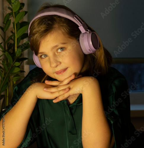 A cute 9-10-year-old girl with headphones leaned on her hands