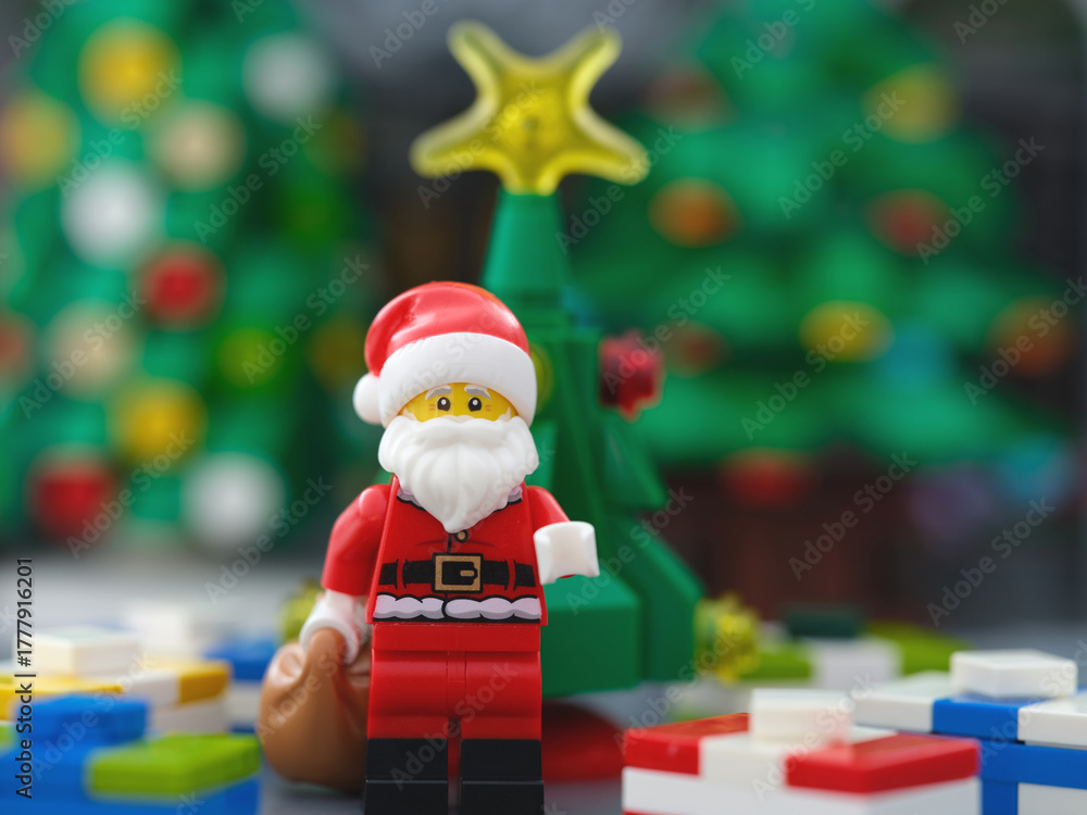 Obraz premium Tambov, Russian Federation - October 23, 2025 A Lego Santa Claus minifigure with a sack of presents standing in front of a Christmas tree and surrounded by gifts.