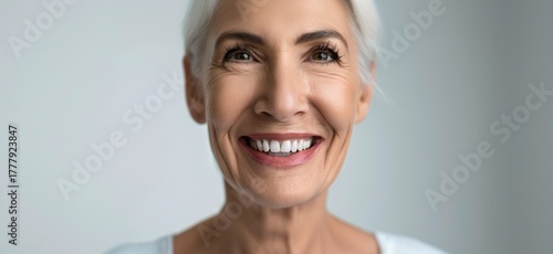 Close-up of a cheerful senior woman with natural gray hair and radiant white smile, representing positivity, wellness, and graceful aging.