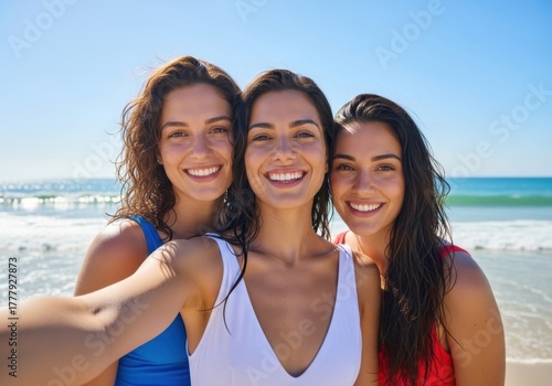 Three smiling young women taking a selfie on a sunny beach with the ocean and clear blue sky in the background