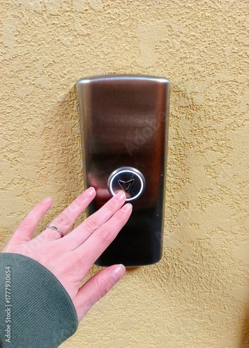 Woman's hand presses the button on the door. Close-up.