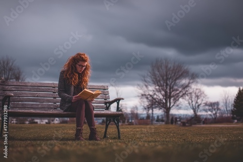 Reading in Serenity: A woman engrossed in a book, seated on a bench, finds a moment of peace amidst the backdrop of a cloudy sky and a serene park.