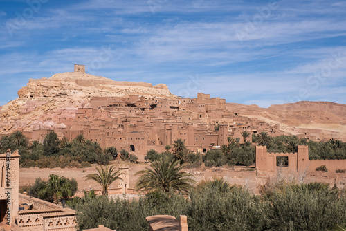 Aerial view of the historic fortified village of Aït Benhaddou in Morocco, featuring traditional mudbrick architecture against a vast desert landscape.