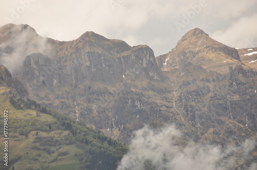 Majestic mountain peaks rise above the clouds in a serene landscape during late afternoon