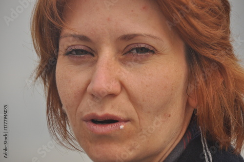 Woman with red hair speaking outdoors on a cloudy day