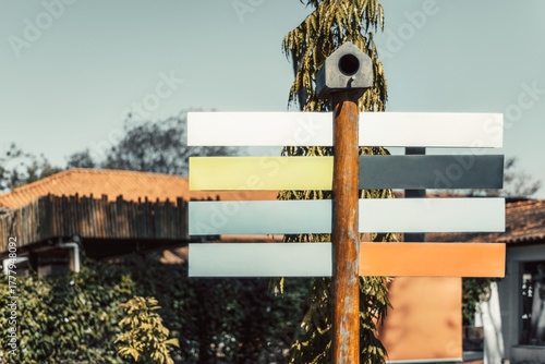 Colorful blank directional sign mockup with empty panels on a wooden pole under bright daylight, perfect template for travel, tourism or navigation design in outdoor environment