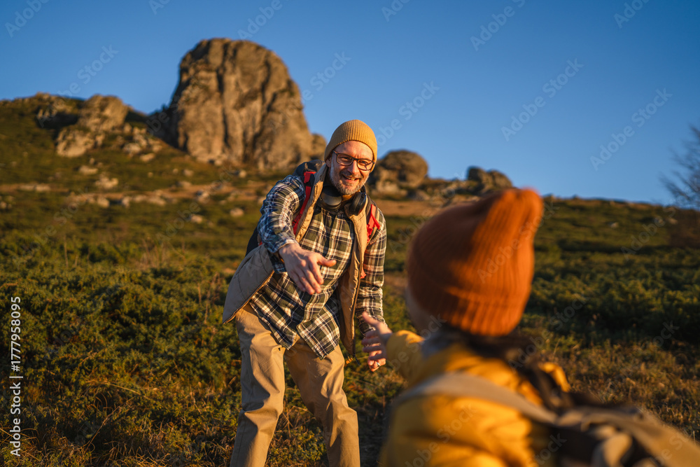 Naklejka premium Father helping child on mountain hike reaching hand
