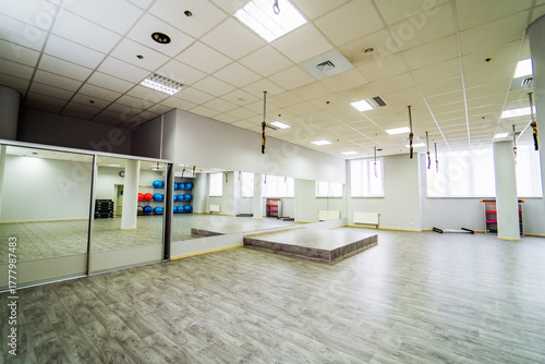Modern fitness studio with mirrors. Bright modern fitness studio with large mirrors, stage platform and training equipment.