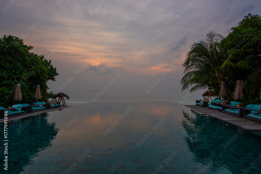 Naklejka premium Tranquil closeup calm sea water waves with palm trees. Reflection on pool. Tropical island beach landscape exotic shore coast. Summer vacation, holiday amazing nature. Relax paradise, Maldives.