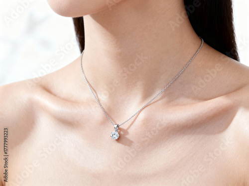 Close up of a woman wearing a silver necklace with a diamond pendant against a white background