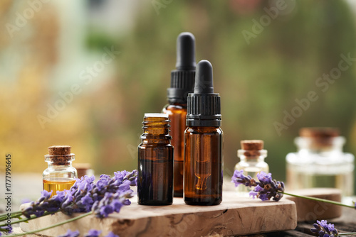 Aromatherapy essential oil in amber bottles with blooming lavender plant outdoors