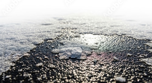 Icy asphalt surface with salt grains and water droplets in winter  