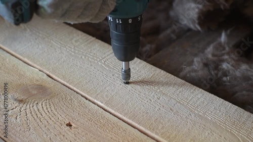 builder screws a self-tapping screw into a board, building houses