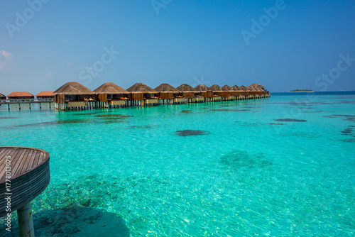 Fototapeta Naklejka Na Ścianę i Meble -  Tranquil closeup calm sea water waves with palm trees. Bungalows background. Tropical island beach landscape exotic shore coast. Summer vacation, holiday amazing nature. Relax paradise, Maldives.