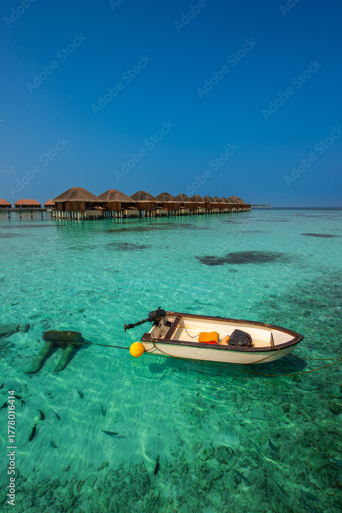 Fototapeta premium Tranquil closeup calm sea water waves with palm trees. Boat and bungalows background. Tropical island beach landscape exotic shore coast. Summer vacation, holiday amazing nature, Maldives.