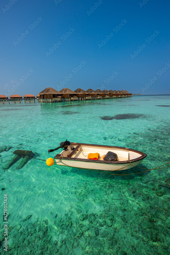 Fototapeta premium Tranquil closeup calm sea water waves with palm trees. Boat and bungalows background. Tropical island beach landscape exotic shore coast. Summer vacation, holiday amazing nature, Maldives.