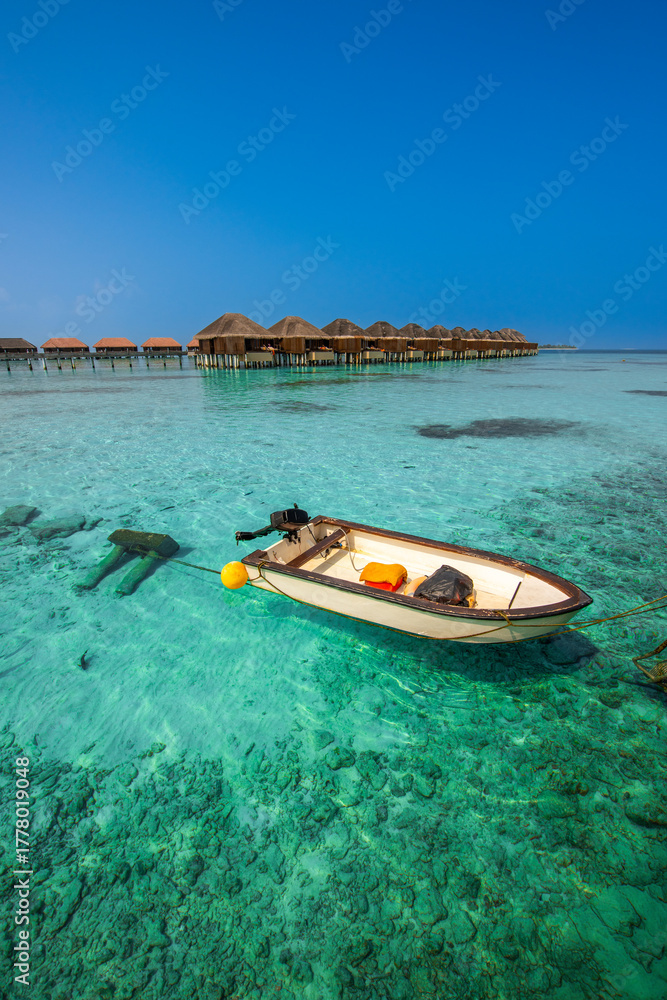 Fototapeta premium Tranquil closeup calm sea water waves with palm trees. Boat and bungalows background. Tropical island beach landscape exotic shore coast. Summer vacation, holiday amazing nature, Maldives.
