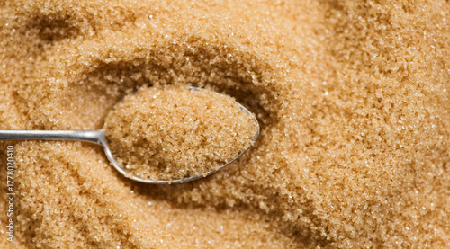 Brown Cane sugar in a spoon close up. Heathy eating, diet concept. Grained brown sugar background, texture. Top view, flat lay, food backdrop. 