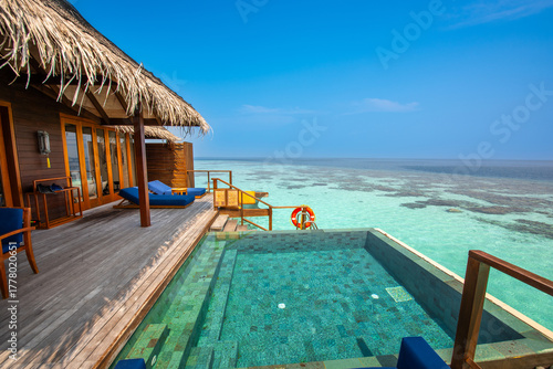 Fototapeta Naklejka Na Ścianę i Meble -  Tranquil closeup calm sea water waves with palm trees. Cabin with pool. Tropical island beach landscape exotic shore coast. Summer vacation, holiday amazing nature. Relax paradise, Maldives.