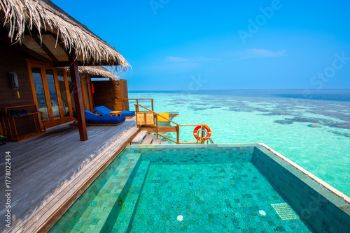 Fototapeta Naklejka Na Ścianę i Meble -  Tranquil closeup calm sea water waves with palm trees. Cabin with pool. Tropical island beach landscape exotic shore coast. Summer vacation, holiday amazing nature. Relax paradise, Maldives.