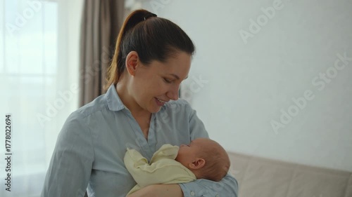 A young, attractive, thirty-year-old brunette woman cradles her infant in her arms. Concept of late motherhood