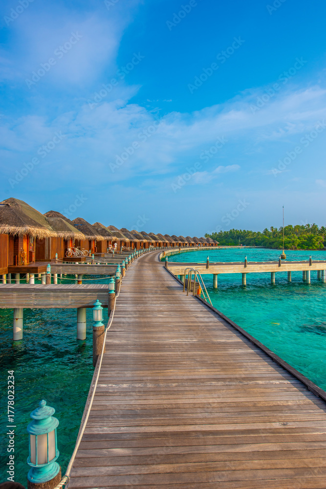 Fototapeta premium Tranquil closeup calm sea water waves with palm trees. Deck with bungalows. Tropical island beach landscape exotic shore coast. Summer vacation, holiday amazing nature. Relax paradise, Maldives.