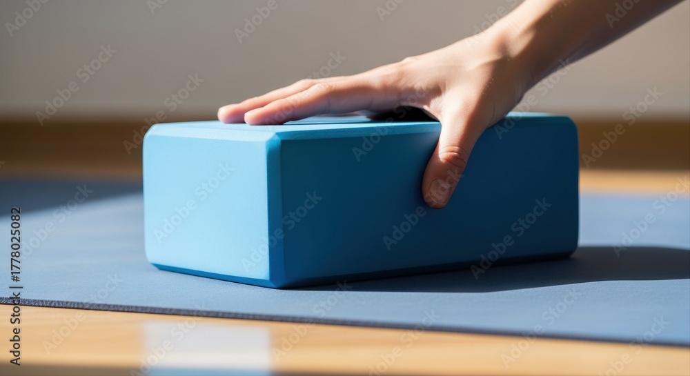 Fototapeta premium person using blue yoga block on mat during sunlight calming session indoors