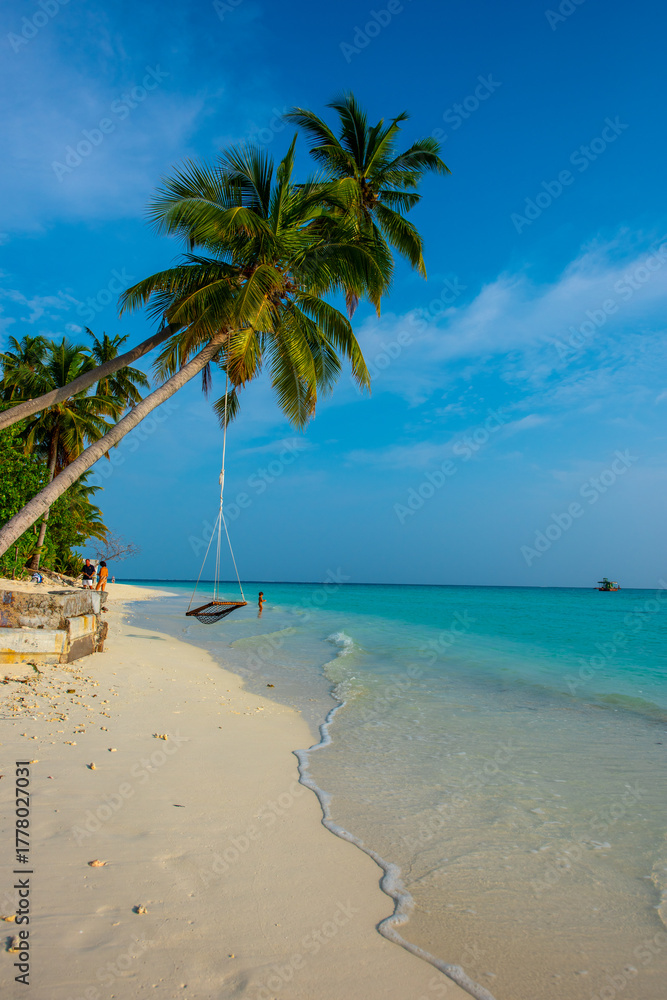 Fototapeta premium Tranquil closeup calm sea water waves with palm trees. Swing on the tree. Tropical island beach landscape exotic shore coast. Summer vacation, holiday amazing nature. Relax paradise, Maldives.
