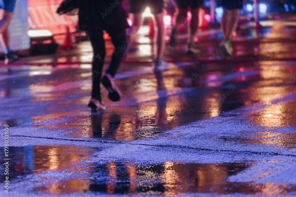 Fototapeta premium Night marathon runners crowd in the rain, sportsmen participants start running the half-marathon in the city streets with night lighting and illumination, group crowd of sportswomen joggers in motion