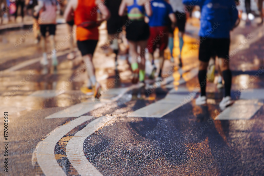 Fototapeta premium Night marathon runners crowd in the rain, sportsmen participants start running the half-marathon in the city streets with night lighting and illumination, group crowd of sportswomen joggers in motion