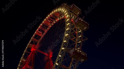 The Wiener Riesenrad, Illuminated giant Ferris Wheel glowing at night against dark sky at Prater Amusement Park, Vienna