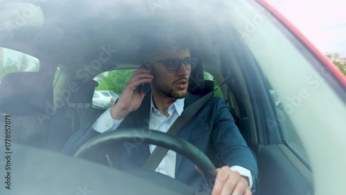 Businessman talking on mobile phone while driving and overtaking, paying attention to the road. Transport, business, technology and people concept. Slow motion