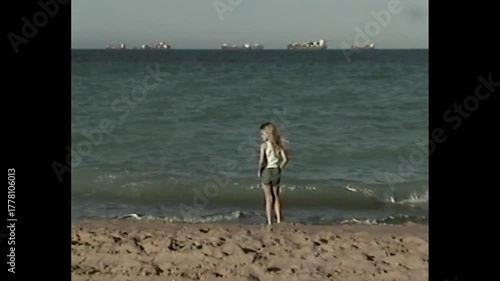 Young girl at edge of sea in vintage 90s vhs home video style