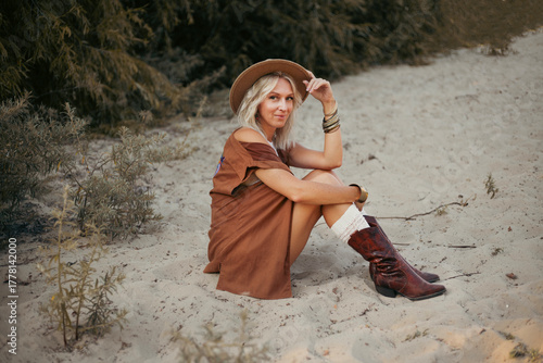 Φωτογραφία Woman in stylish outfit relaxing on sandy beach surrounded by greenery in warm s