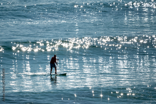 Active senior Australian man ride on a wave with SUP in the Pacific ocean