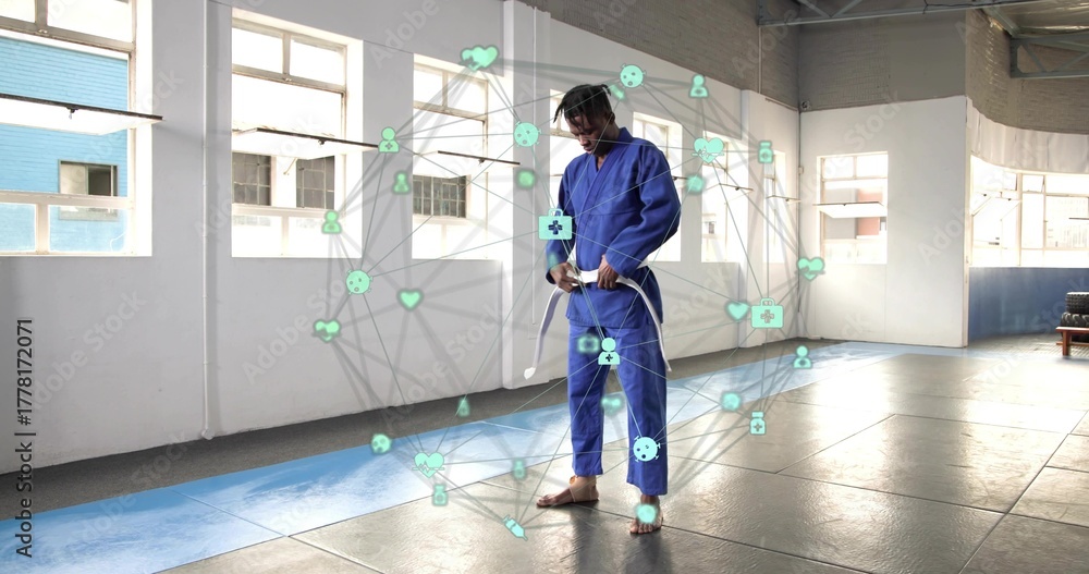 Obraz premium Tying white belt martial artist wearing blue gi inside training hall, with digital health network