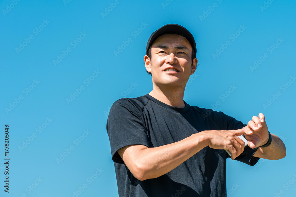 Fototapeta premium A middle-aged man in sportswear using a smartwatch, pedometer, and pedometer to manage his health and wellness 