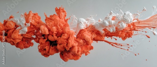 Orange and white paint swirling in water against a gray backdrop